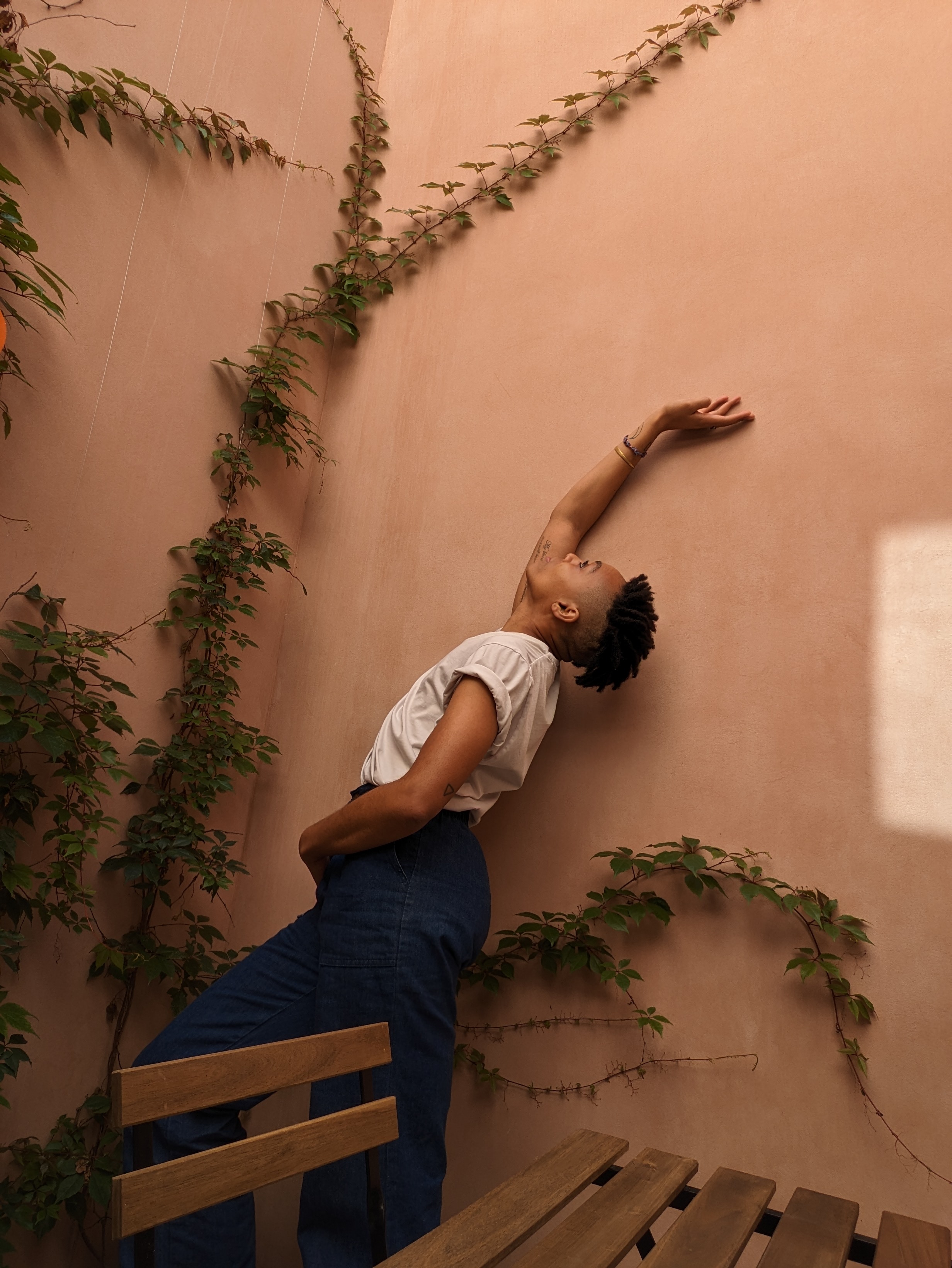 image of zel in a courtyard posing to the side with one arm up and head lifted to the sky