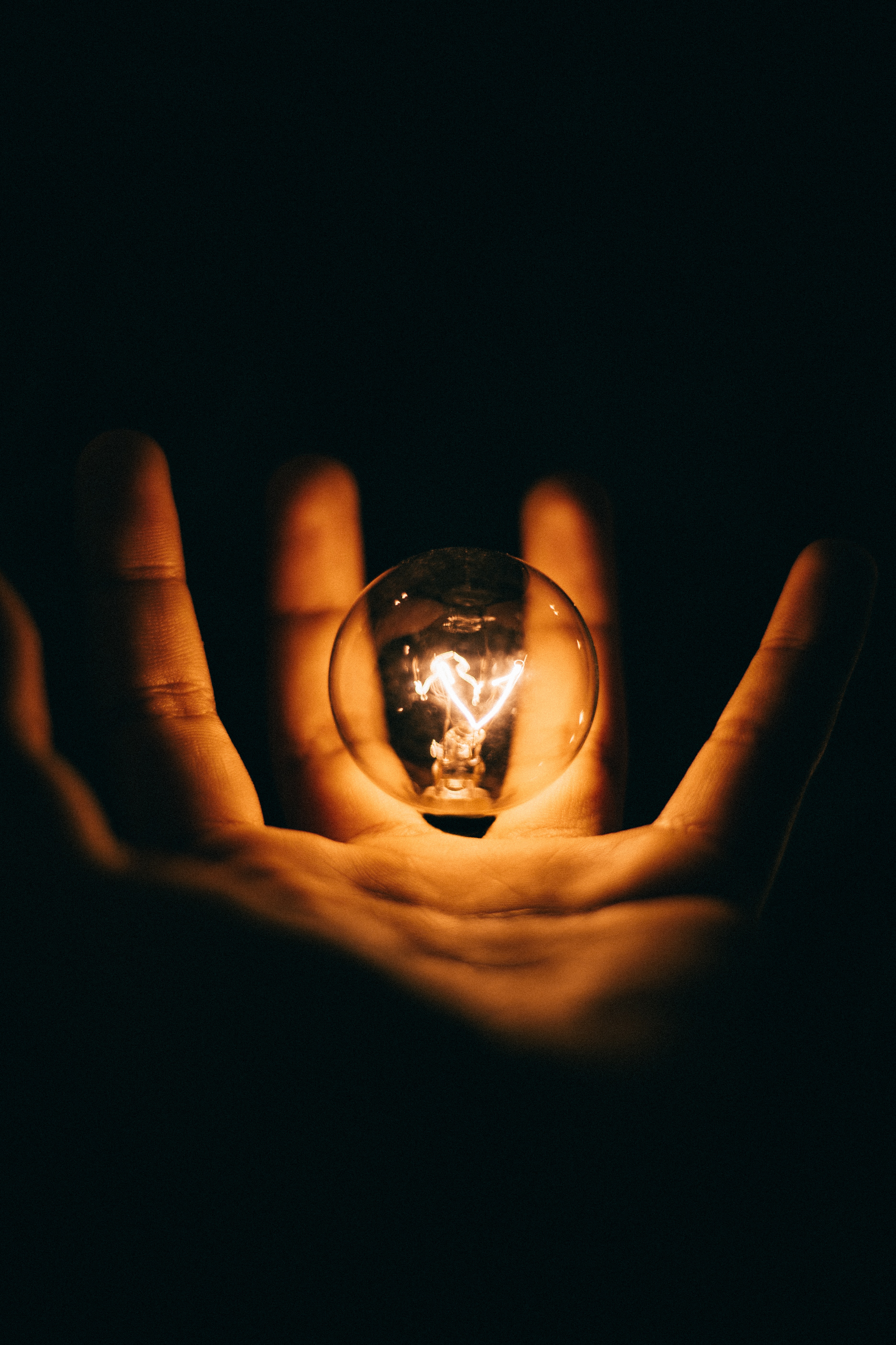 hand reaching out underneath a floating light bulb