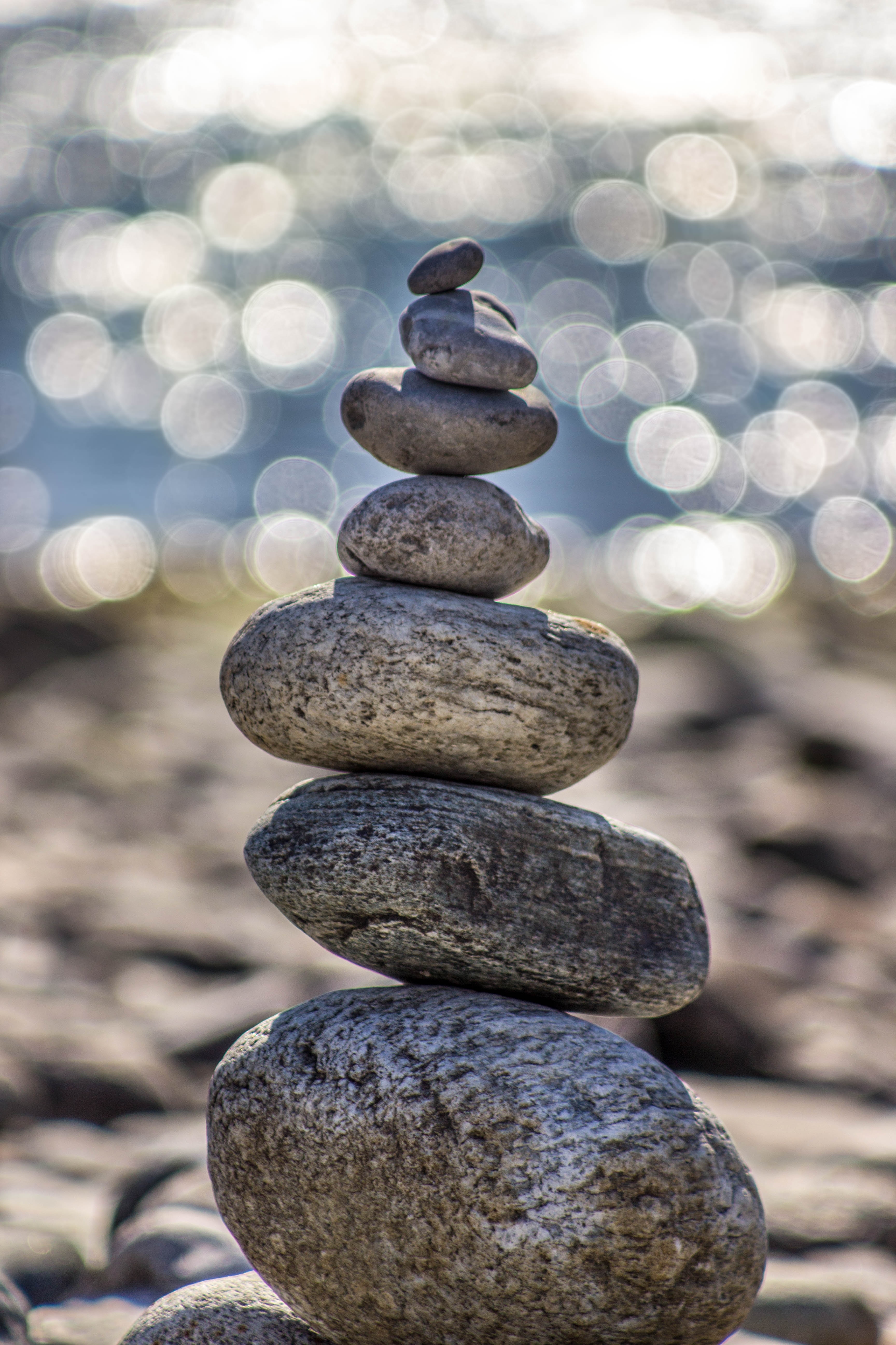 rocks carefully stacked on top of each other in a pyramidal shape with a blurred background that suggests water droplets