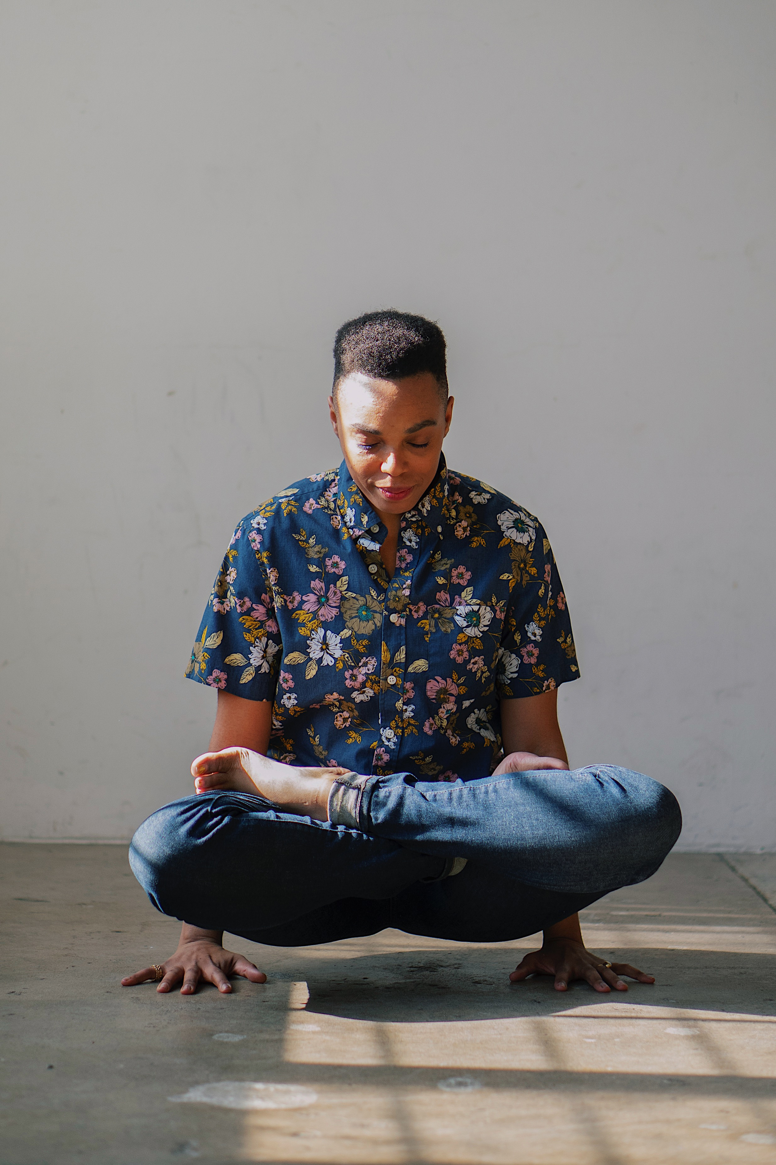 photo of zel wearing a floral button down while holding lifted lotus pose